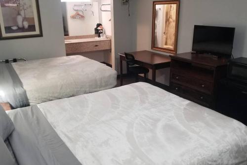 een hotelkamer met 2 bedden, een bureau en een spiegel bij OSU 2 Queen Beds Hotel Room 136 Wi-Fi Hot Tub Booking in Stillwater