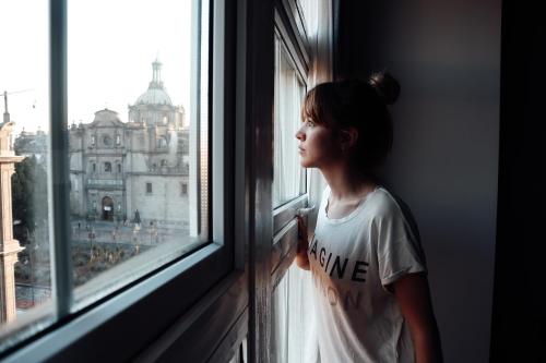 a woman looking out of a window at a building at Zocalo Central & Rooftop Mexico City in Mexico City