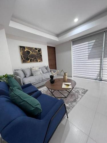 a living room with a blue couch and a table at Precioso departamento cerca de Plaza Galerías in Guadalajara