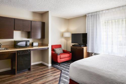 a hotel room with a bed and a red chair at TownePlace Suites Tempe at Arizona Mills Mall in Tempe