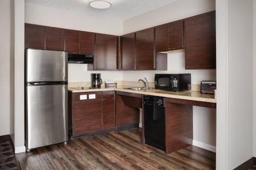 a kitchen with wooden cabinets and a stainless steel refrigerator at TownePlace Suites Tempe at Arizona Mills Mall in Tempe