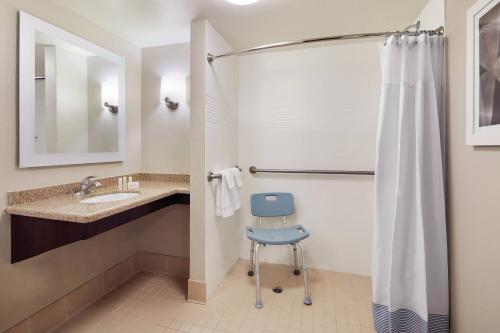a bathroom with a shower and a blue chair at TownePlace Suites Tempe at Arizona Mills Mall in Tempe