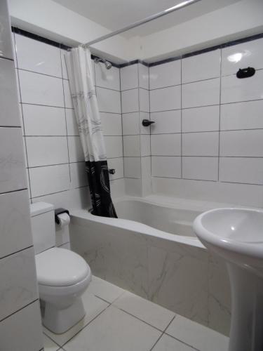 a bathroom with a toilet and a tub and a sink at Hotel Montecristo Cusco in Cusco