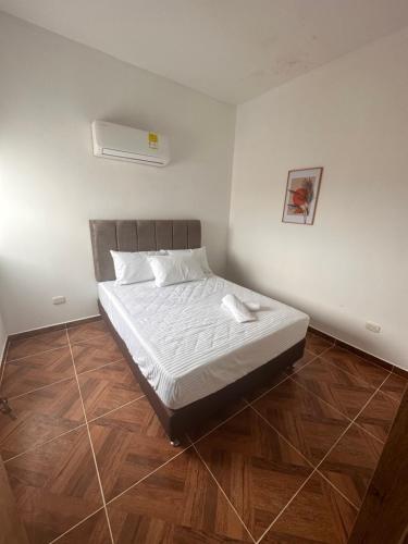 een slaapkamer met een bed met witte lakens en houten vloeren bij Apartamento nuevo en Coveñas in Coveñas