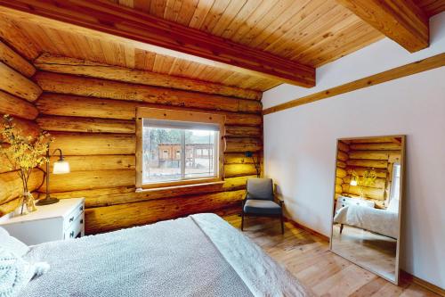 Ponderosa Log Cabin في كلي إلوم: غرفة نوم بجدران خشبية وسرير وكرسي