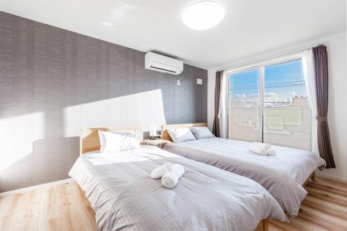 1 Schlafzimmer mit 2 Betten und einem großen Fenster in der Unterkunft THE SUN in Sapporo