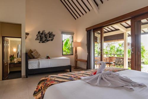 a bedroom with two beds and a swan on the bed at Alamanda Lovina Resort in Lovina