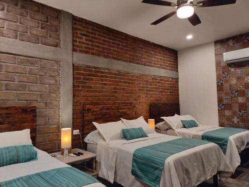 - une chambre avec 2 lits et un mur en briques dans l'établissement Hotel Villa de Urike, à Urique