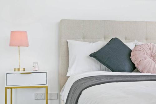 a bedroom with a bed with a pink pillow and a lamp at Aircabin｜Mascot｜Spacious & Modern｜Walk to station in Sydney