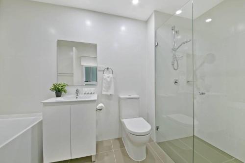 a white bathroom with a toilet and a shower at Aircabin｜Mascot｜Spacious & Modern｜Walk to station in Sydney