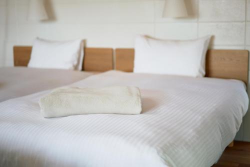 un letto bianco con un asciugamano pieghevole di オーシャンビュー非日常を味わえる空間プライベートバーベキューm yomitan nagahama a Yomitan