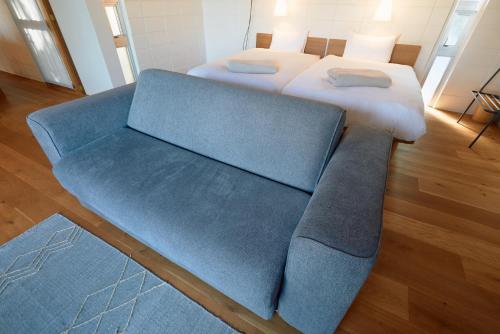 a bedroom with two beds and a blue couch at オーシャンビューの静かな84平米の空間で暮らすように泊まる宿m yomitan nagahama in Yomitan