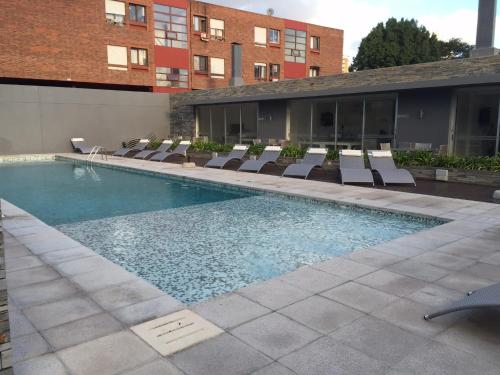 a swimming pool with lounge chairs and a building at Torre del mar in Punta del Este