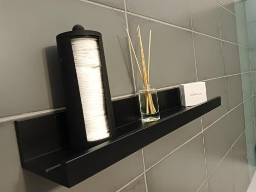 a black shelf on a wall with a candle and sticks at Apartmán Hybešova2 in Brno