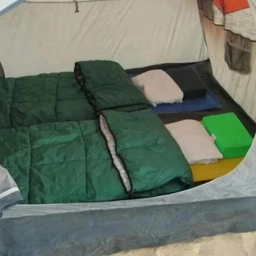 a bed in a tent with green sheets and pillows at استارز كامب in Bawiti