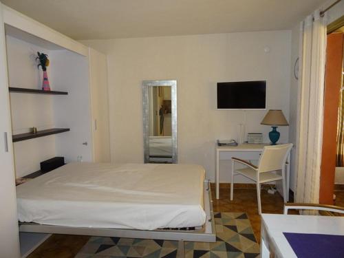 une chambre avec un lit, un bureau et une télévision dans l'établissement Appartement à Hyères avec parking, véranda et cuisine équipée - FR-1-335-177, à Hyères