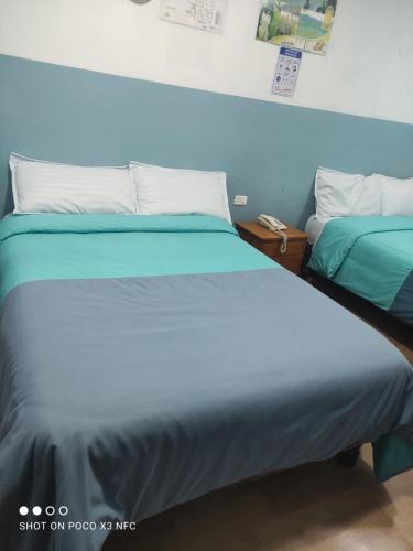 2 letti posti uno accanto all'altro in una camera da letto di Hostal puerta del sol a Quito