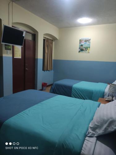 Habitación de hotel con 2 camas y TV de pantalla plana. en Hostal puerta del sol en Quito
