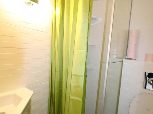 La salle de bains est pourvue d'une douche avec rideau de douche vert. dans l'établissement Maison clim. proche mer, terrasse et parking privatisé, 6 pers. - FR-1-307-230, au Grau-du-Roi