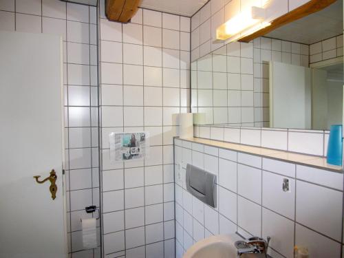 a white tiled bathroom with a sink and a mirror at Apartment in Schultenbrook with garden in Metelsdorf