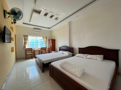 a bedroom with two beds and a table and a window at ALOHA HOTEL SUỐI MÂY PHÚ QUỐC in Phu Quoc