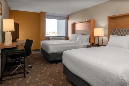 a hotel room with two beds and a desk at Holiday Inn Boston - Dedham Hotel & Conference Center by IHG in Dedham
