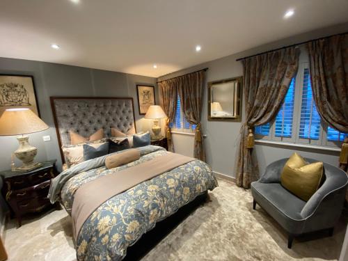 a bedroom with a bed and a chair and windows at Executive Corporate Penthouse in Woking