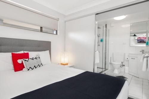 Schlafzimmer mit einem großen Bett und einem roten Kissen in der Unterkunft L'Amor Holiday Apartments in Yeppoon