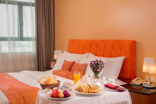 a hotel room with a tray of food on a bed at Fortuna Hotel Hanoi in Hanoi