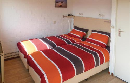 a bedroom with a bed with colorful sheets and pillows at Two-Bedroom Holiday Home In Callantsoog in Callantsoog