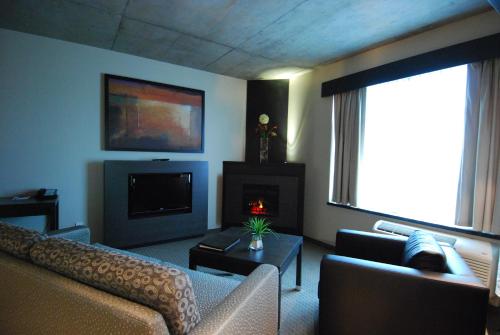 a living room with a couch and a tv at Grand Times Hotel in Quebec City