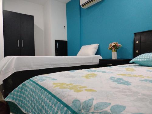 a bedroom with two beds and a blue wall at Casa España in Sincelejo