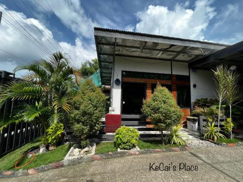 a house with a porch with trees in front of it at KeCai’s Place in Digos