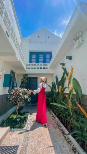 a woman in a red dress standing in front of a house at CERIA HOTEL at Alun Alun Yogyakarta in Yogyakarta