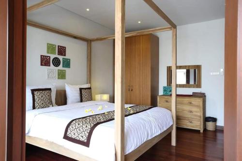 a bedroom with a canopy bed and a wooden dresser at Tolgay Living Villas in Seminyak