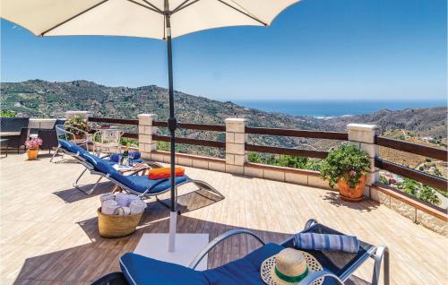 a patio with chairs and an umbrella on a balcony at Beautiful Home In Cómpeta in Sayalonga