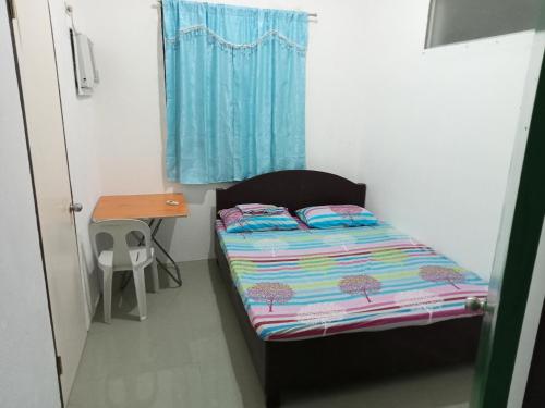 a small bedroom with a bed and a table at RGR CAMIGUIN TRAVEL TOUR SERVICES AND PENSION HOUSE in Mambajao