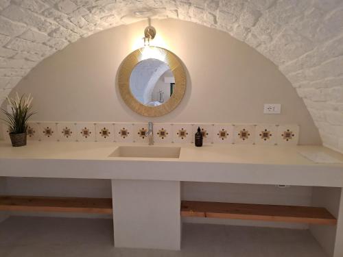 La salle de bains est pourvue d'un lavabo et d'un miroir. dans l'établissement Palazzo AD 1892 - SUITES & SPA, à Ostuni