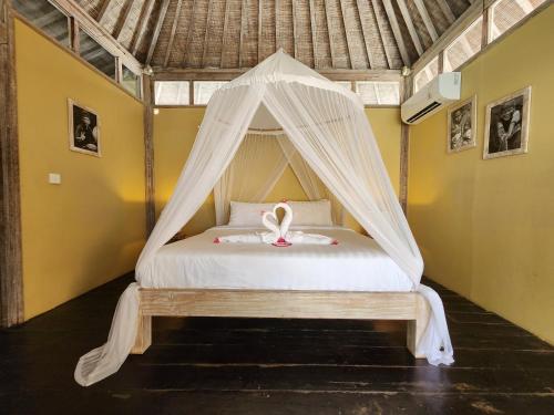 a bed in a room with a mosquito net at Villa Bamboo in Gili Trawangan