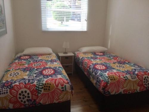 a bedroom with two beds and a window at Dutchies Beachside Retreat in Nelson Bay