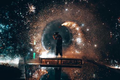 a man standing in front of a fountain with fireworks at Kupu Kupu Phangan Beach Villas & Spa by L'Occitane - SHA Plus in Haad Pleayleam