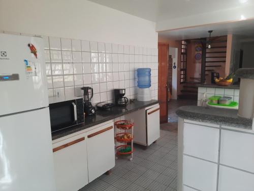 a kitchen with white cabinets and a black counter top at Vila Santa Fé in Porto Seguro