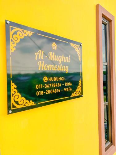 a sign on the side of a yellow wall at Al-Mughni Homestay in Pasir Gudang