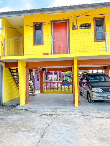 un edificio amarillo con un coche aparcado delante de él en Al-Mughni Homestay, en Pasir Gudang