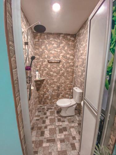 a bathroom with a toilet and a stone wall at Al-Mughni Homestay in Pasir Gudang