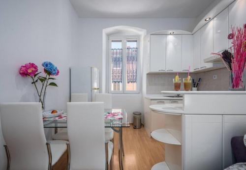 eine weiße Küche mit einem Glastisch und weißen Schränken in der Unterkunft Apartment Ariana - central & comfy in Poreč