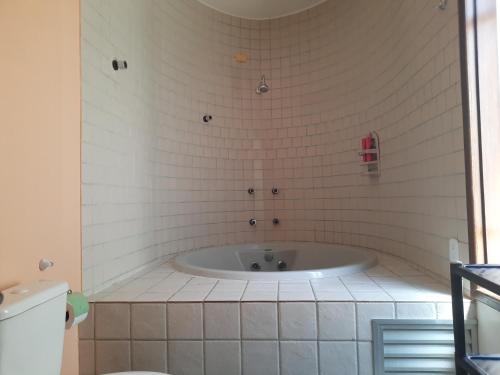 La salle de bains est pourvue d'une baignoire et de carrelage blanc. dans l'établissement Vila Santa Fé, à Porto Seguro