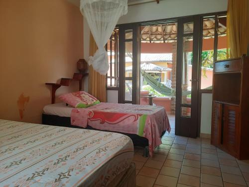 a hotel room with two beds and a balcony at Vila Santa Fé in Porto Seguro