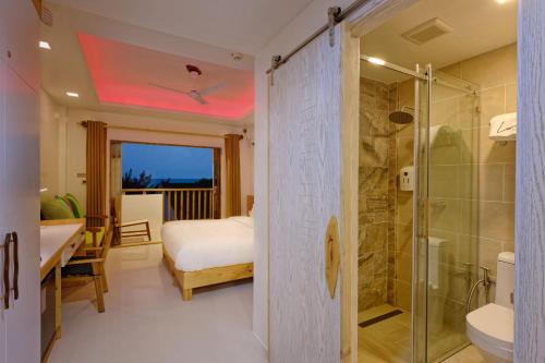 a bathroom with a shower and a bed and a sink at Luau Beach Inn, Maldives in Fulidhoo