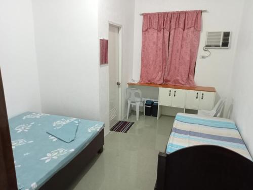 a room with two beds and a window and a desk at RGR CAMIGUIN TRAVEL TOUR SERVICES AND PENSION HOUSE in Mambajao